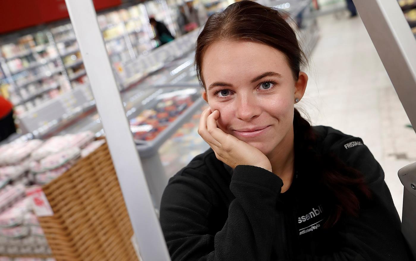 Ung kvinna vilar hakan i ena handen och ler in mot kameran på ett varmt och lugnt sätt